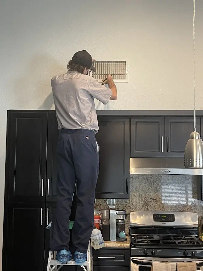 Technician inspecting an air vent during HVAC service in Marrero